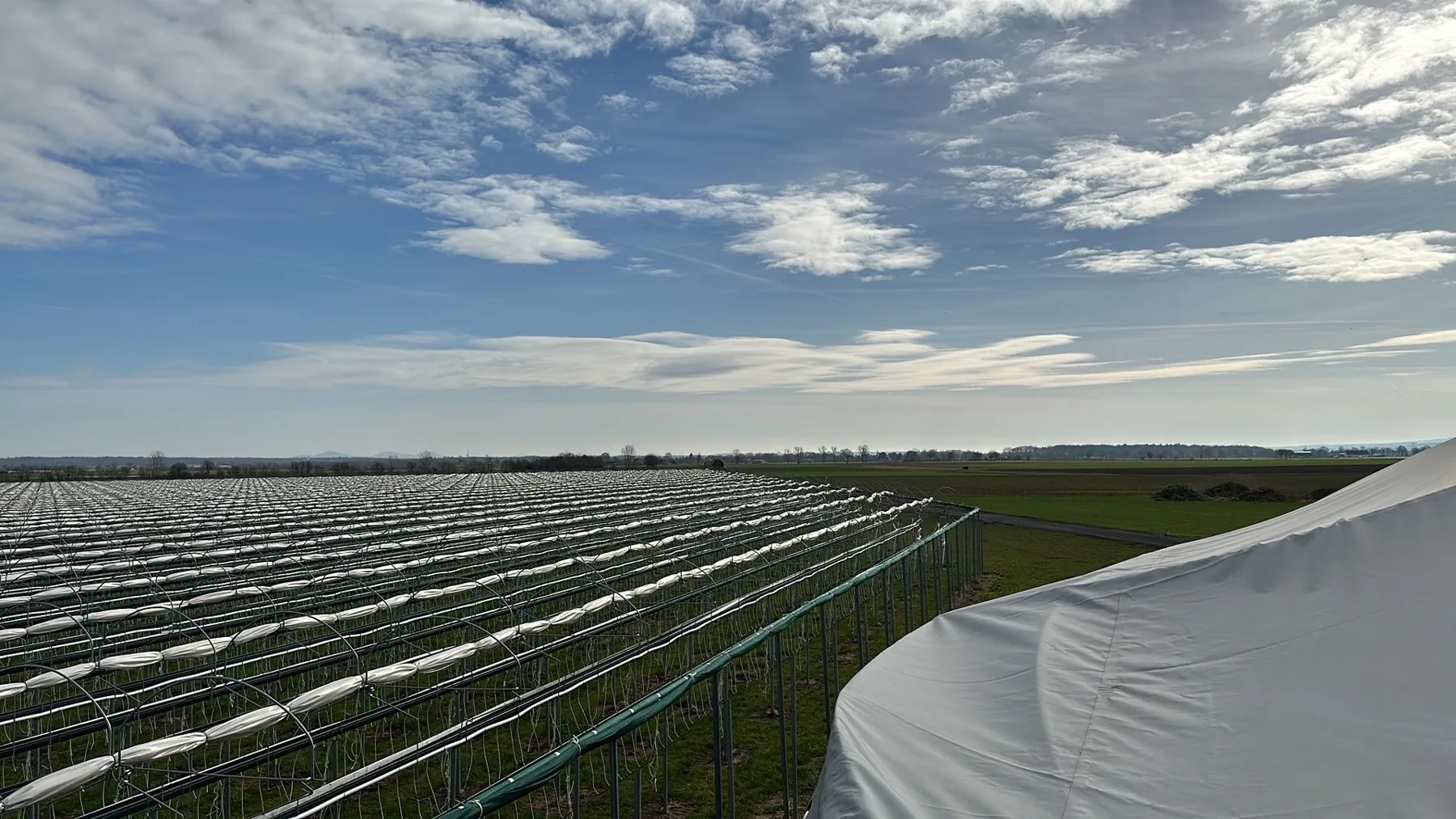 Teeltvelden en een witte tank onder een weidse lucht